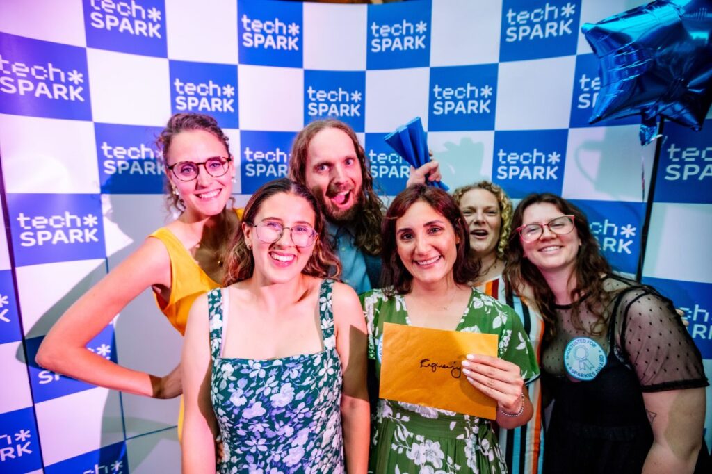 a group of 5 women and a man celebrate winning an award