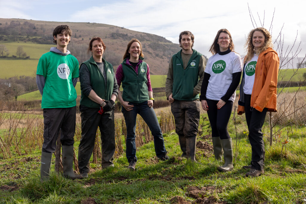 NPK and Stump Up For Trees team photo on the tree nursery with Welsh hills in the background.